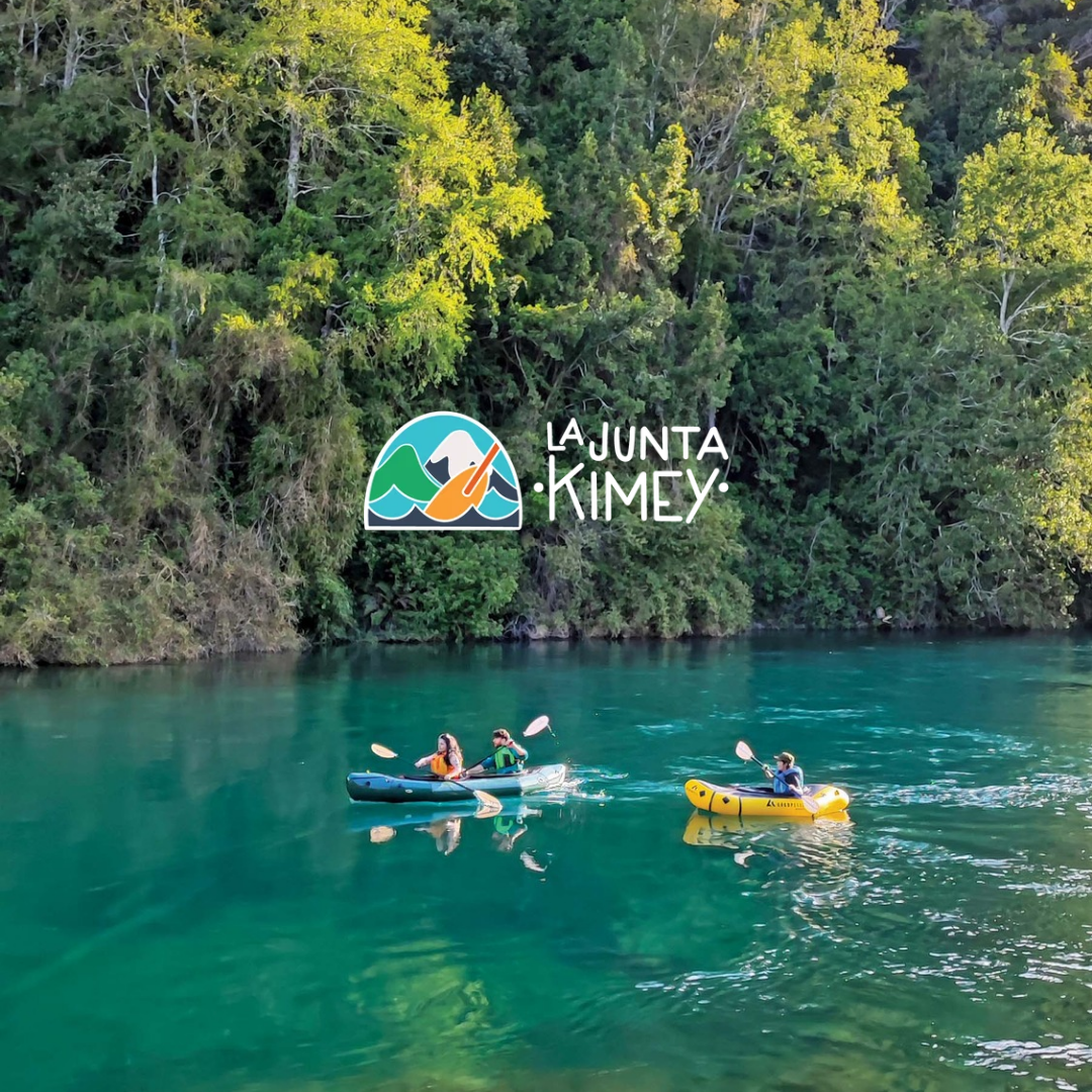 Personas navegando en kayak sobre aguas turquesas rodeadas de bosque nativo junto a La Junta Kimey en Panguipulli Sietelagos.