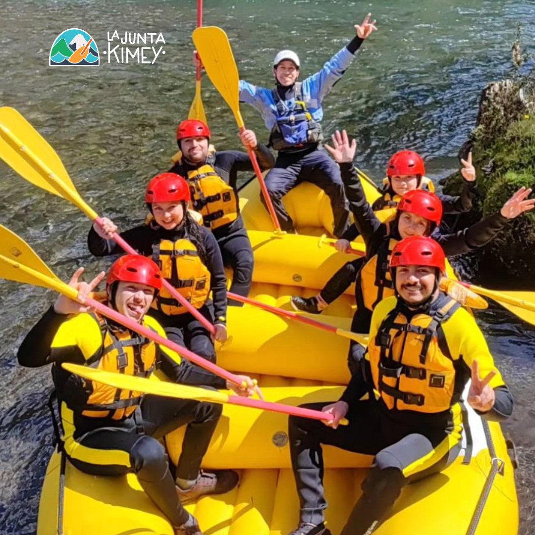 Grupo de personas realizando rafting con equipamiento de seguridad en un río de Panguipulli junto a La Junta Kimey.