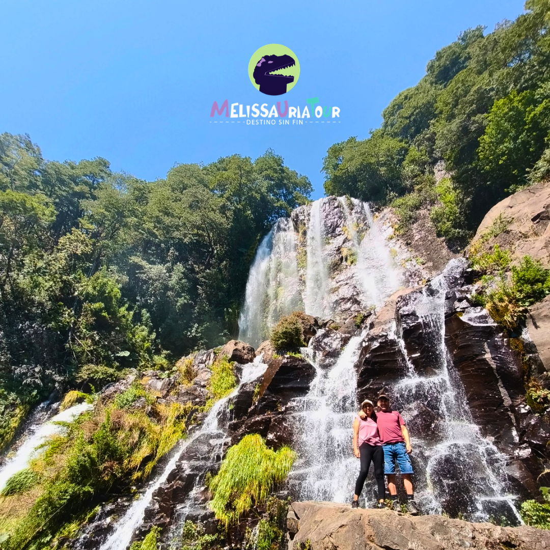 Visitantes junto a una cascada rodeada de bosque nativo en una excursión de Melissauria Tour en Panguipulli Sietelagos.