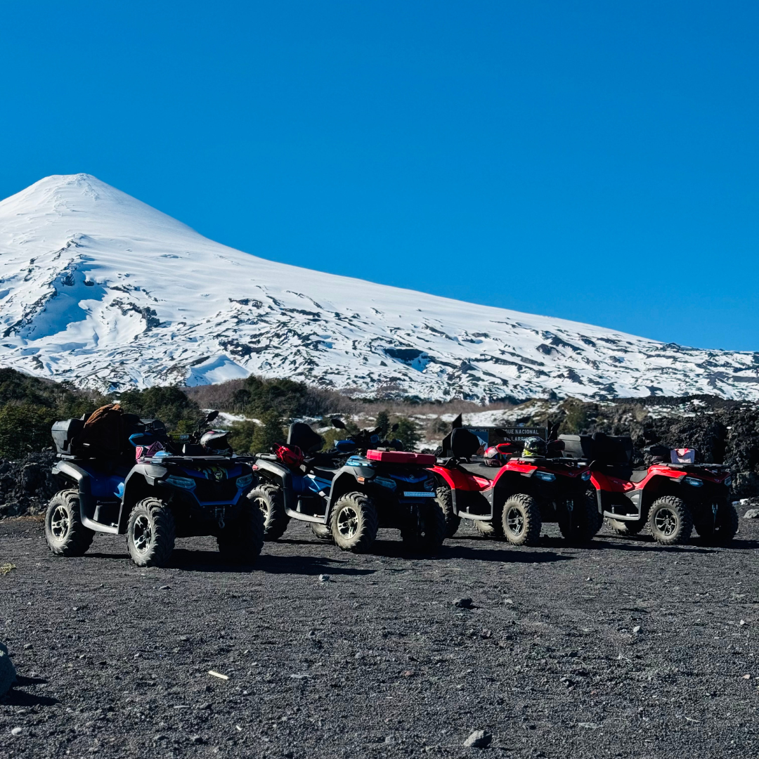 Grupo de cuatrimotos estacionadas frente a un paisaje volcánico nevado en el entorno del Parque Nacional Villarrica.
